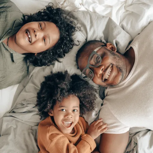 Two kids and their dad lay together in bed.